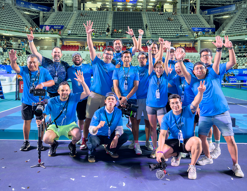 Fotografía del equipo piso 8 en un estadio de tenis, se muestran contentos